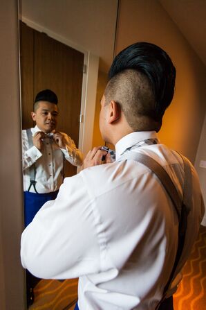 Groom Fastens his Bowtie in the Mirror