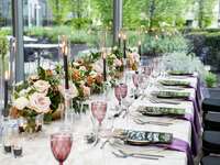 modern romantic wedding tablescape with low rose centerpieces, black taper candles, menu cards, purple water goblets and linen napkins