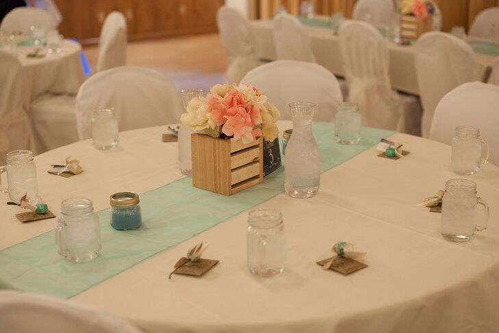 Melissa and Dustin chose a playful pink, ivory and mint color palette for the reception, both giving the Silverthorne Town Pavilion a cheerful vibe, while tying into the wedding’s vintage theme. The couple decorated the reception tables with pale mint table runners and arrangements of fabric flowers displayed in small wooden crate vases, which Melissa handcrafted herself.