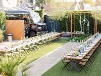 outdoor party at backyard venue with two long wooden tables lined up side by side