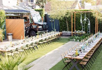 outdoor party at backyard venue with two long wooden tables lined up side by side