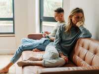 Frustrated couple sitting on couch at home