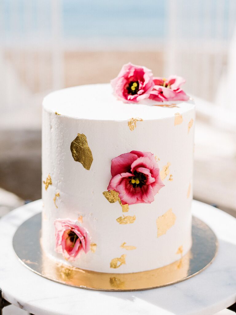 small one tier wedding cake with pink flowers and gold leaf