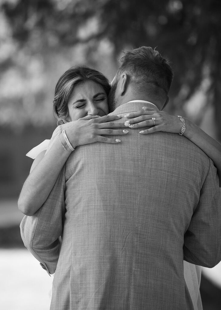 Black and White Photo of Bride Embracing Groom Featuring Bracelets and a Ring