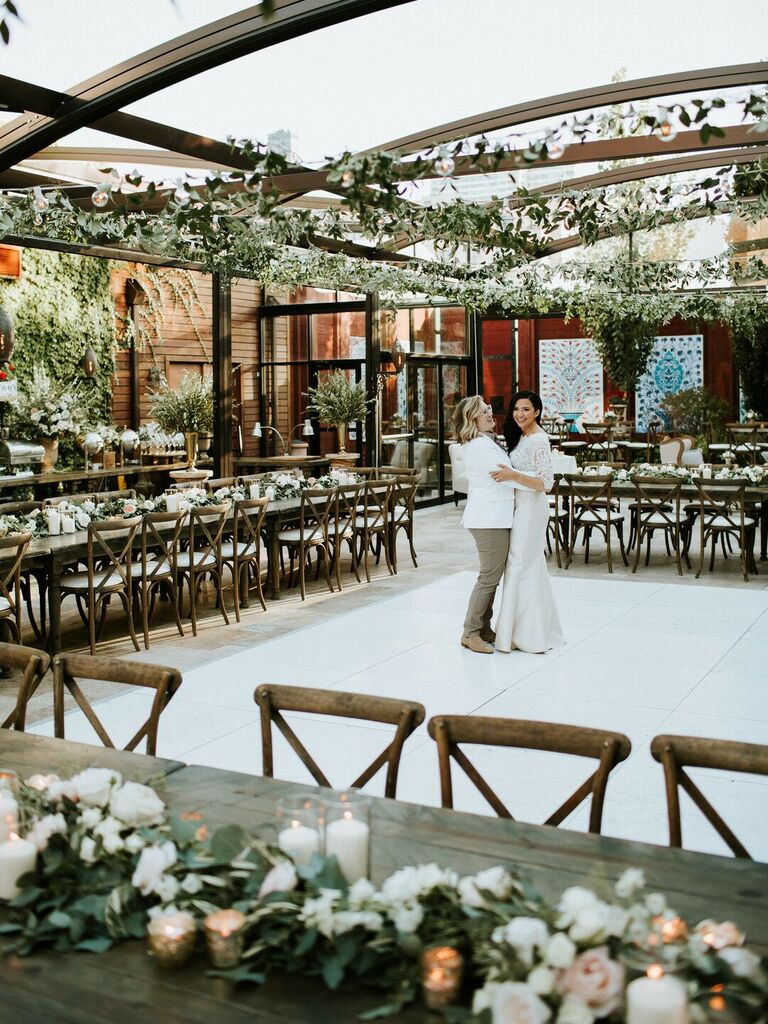 2023 wedding reception trend two brides share private last dance at their wedding reception in an empty venue