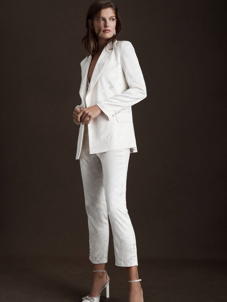 Model wears a fitted white suit set with cropped pants. 