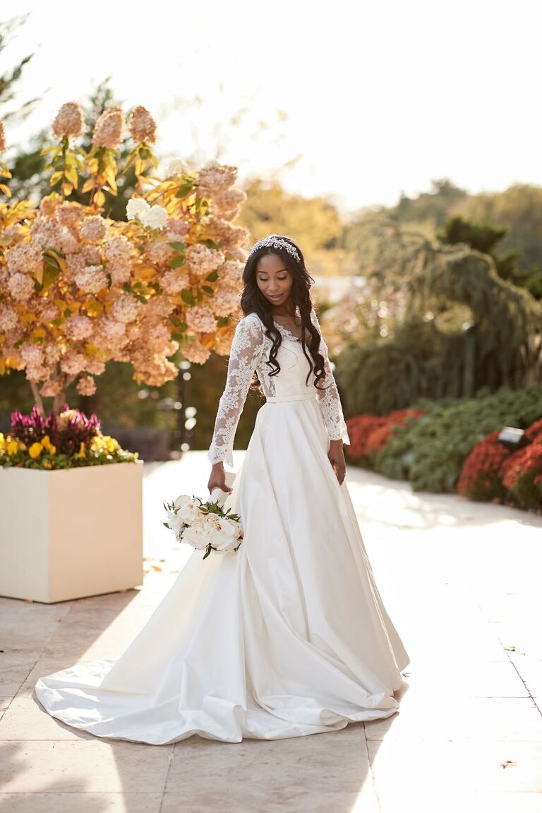 Bride in long-sleeve wedding dress holding white bouquet