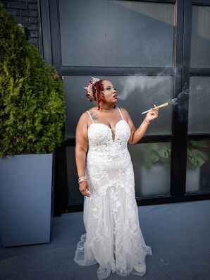Bride in Fitted Lace Gown and Crown Smoking Outside Industrial Venue