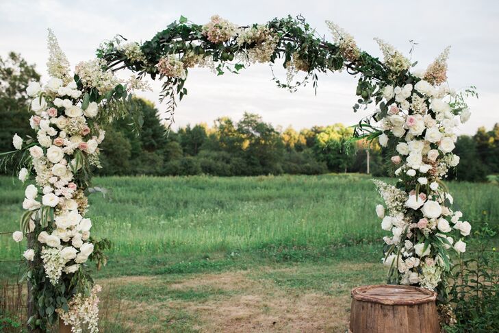 Megan and Jordan went big on flowers, having Seagrass Florals fill the serene natural setting with lush arrangements of garden-inspired blooms and textured wildflowers. For the ceremony, the aisles were lined with glass vases overflowing with fresh, colorful blooms. But it was the wedding arch that truly brought the decor to life. The elaborate structure,  dripping in hydrangeas, roses, olive leaves, vines and wheat, provided a striking backdrop for the couple’s vows.