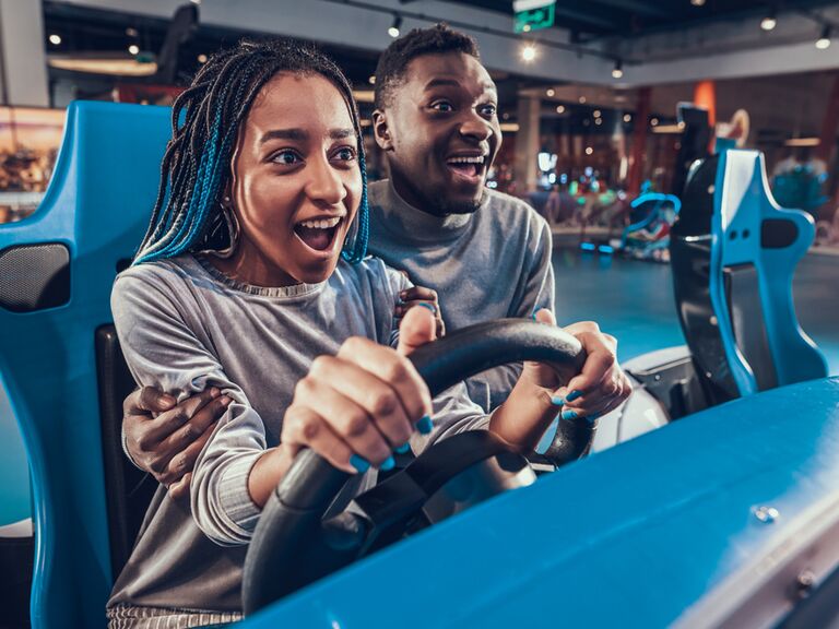 A couple enjoy a racing game together at a video game arcade