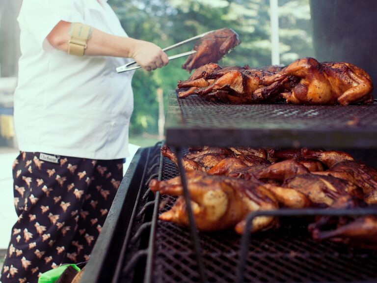 Caterer making barbecue chicken at wedding reception.