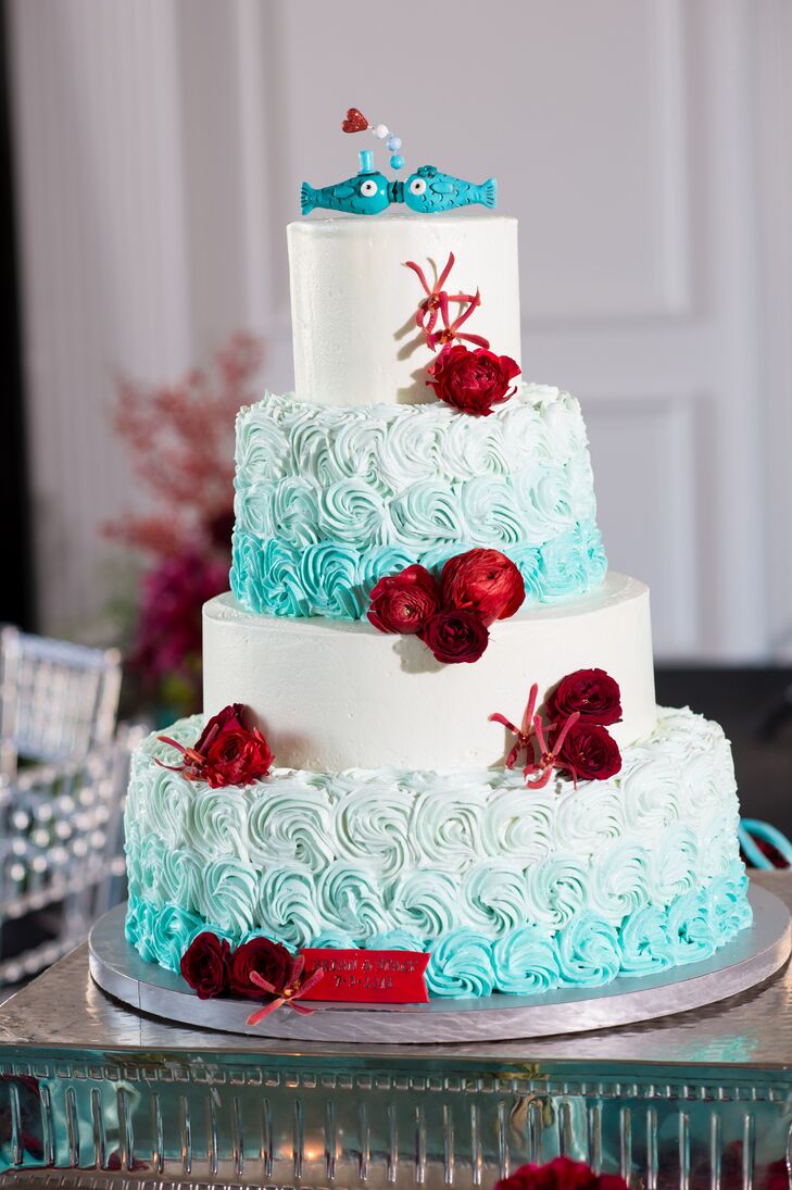 The nautical four tier wedding cake featured an ombre swirl pattern on alternating tiers with red floral accents and a whimsical fish cake topper.