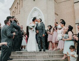 bride and groom kiss on steps of church after christian wedding ceremony