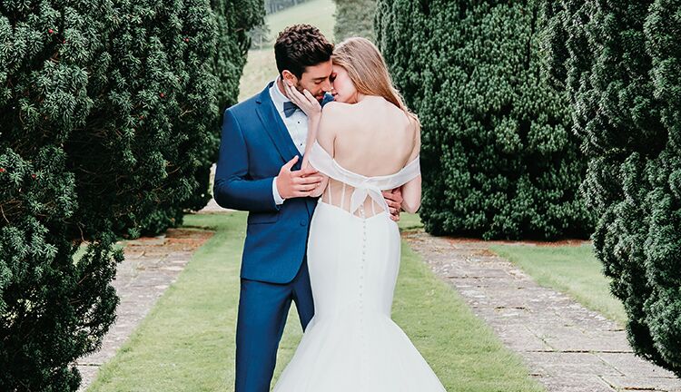 bride with low back wedding dress embracing groom