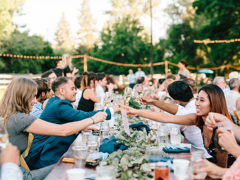 Long table of friends and family at a wedding reception.
