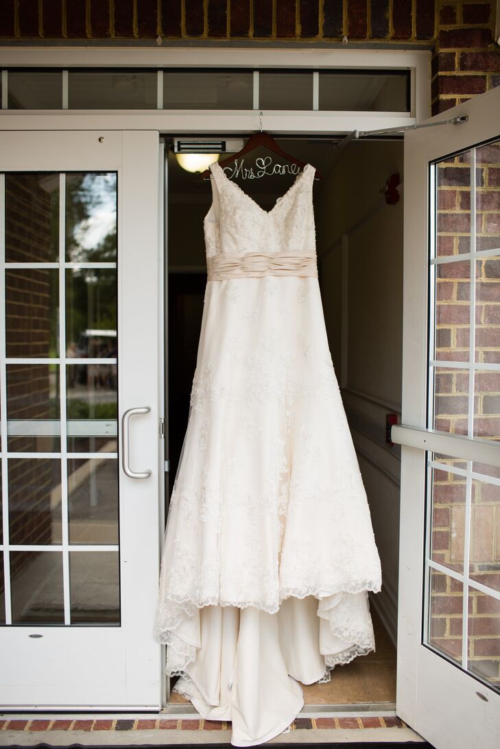 The bride wore a champagne wedding dress designed by Alfred Angelo with a v-neck going down the front and back. The sheer laced top layer of the dress had subtle beading and a small train.