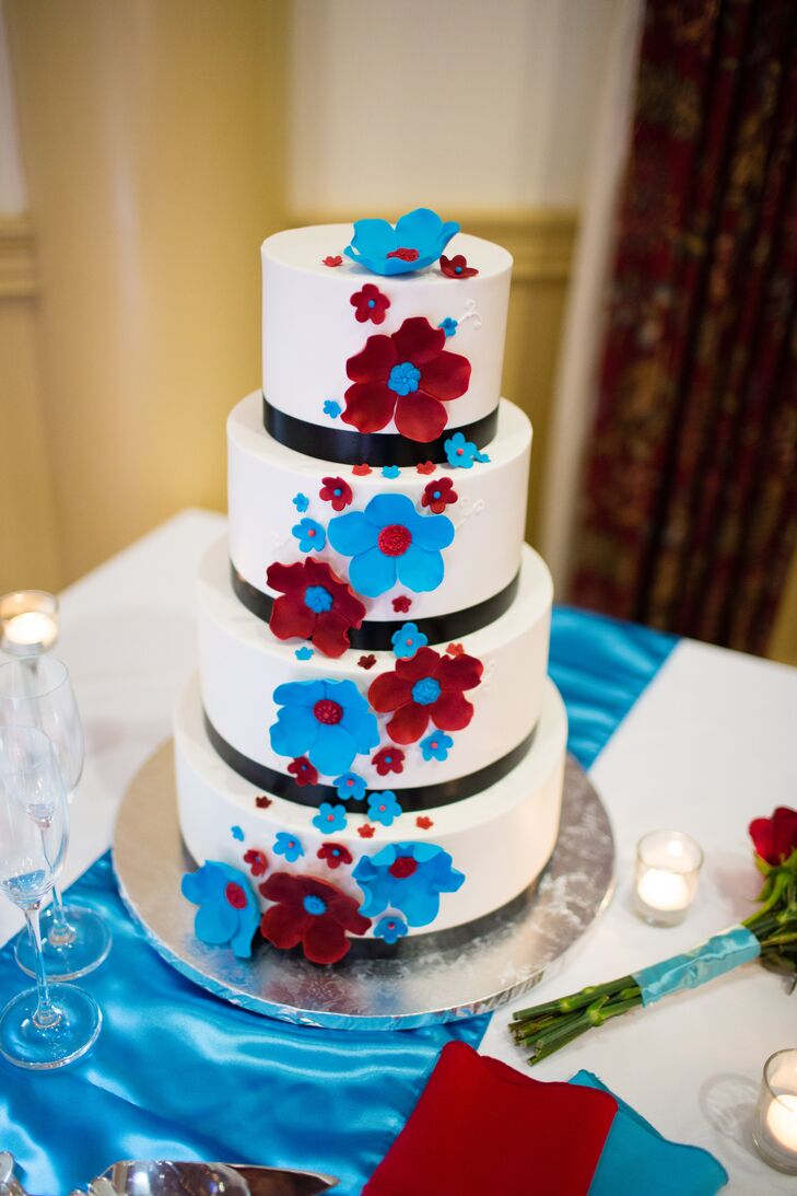The four-tiered white almond cake had two tiers filled with white chocolate, while the other two were filled with raspberry. The cake was covered in buttercream frosting and accented with teal and red gum paste flowers.