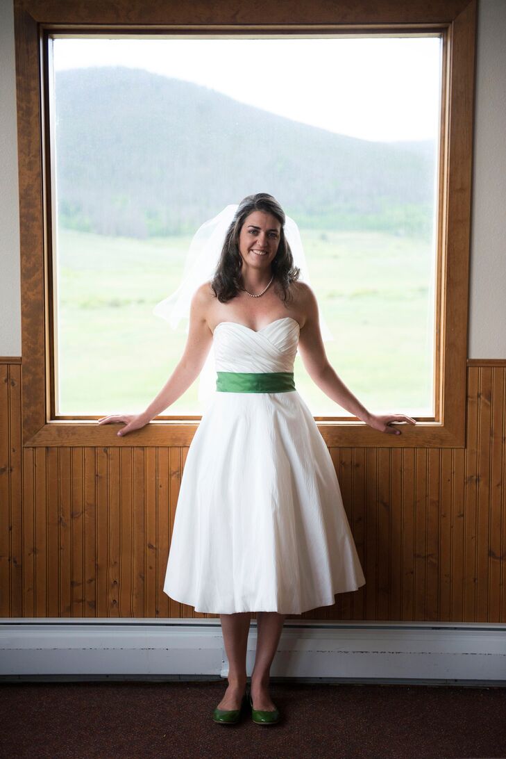 Elizabeth wore a more traditional strapless wedding dress that she altered to be tea length. She completed her look with an elbow-length veil made from her extra wedding dress and emerald green belt.