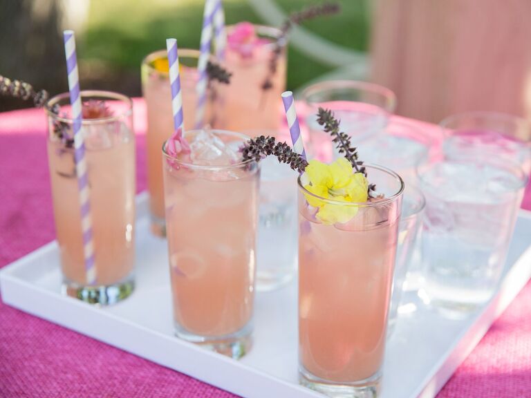 serving tray of pink lemonade in tall glasses with lavender sprigs and striped paper straws