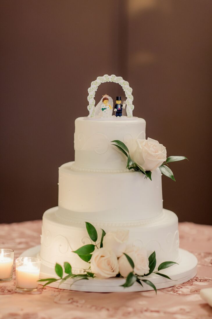 Kate and David opted for a traditional white wedding cake. Each layer was lined with delicate detailing and ivory roses. The topper, a fun surprise, was made of a Lego bride and groom under a miniature arbor.