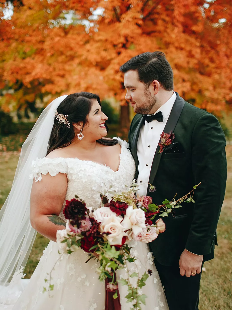 The happy couple gaze into each others eyes before a background of warm, autumnal trees.