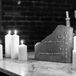 A black-and-white photo of the cocktail hour bar, featuring dim candles and a broken stone sign featuring "His" and Hers" signature drinks at a modern and elegant loft wedding.