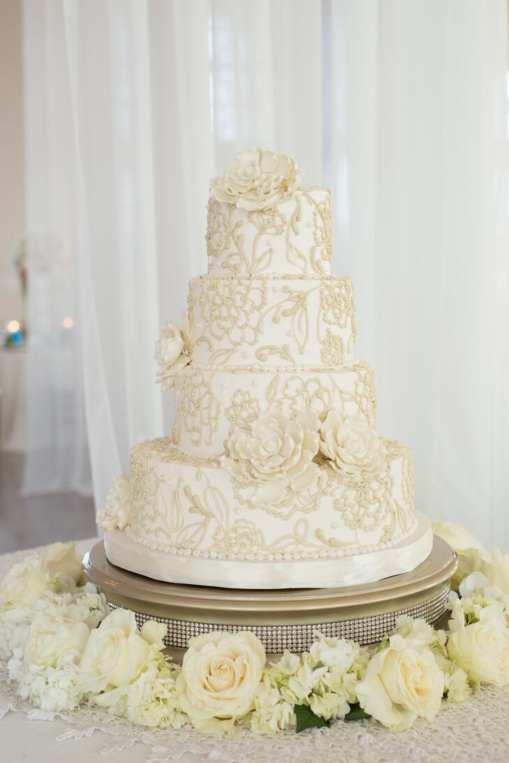 Honey's Cakes created a stunning four-tier cake with exquisite ivory floral details and sugar flowers. A wreath of ivory flowers surrounding the gold cake stand, embellished with rhinestones, completed the eye-catching display.