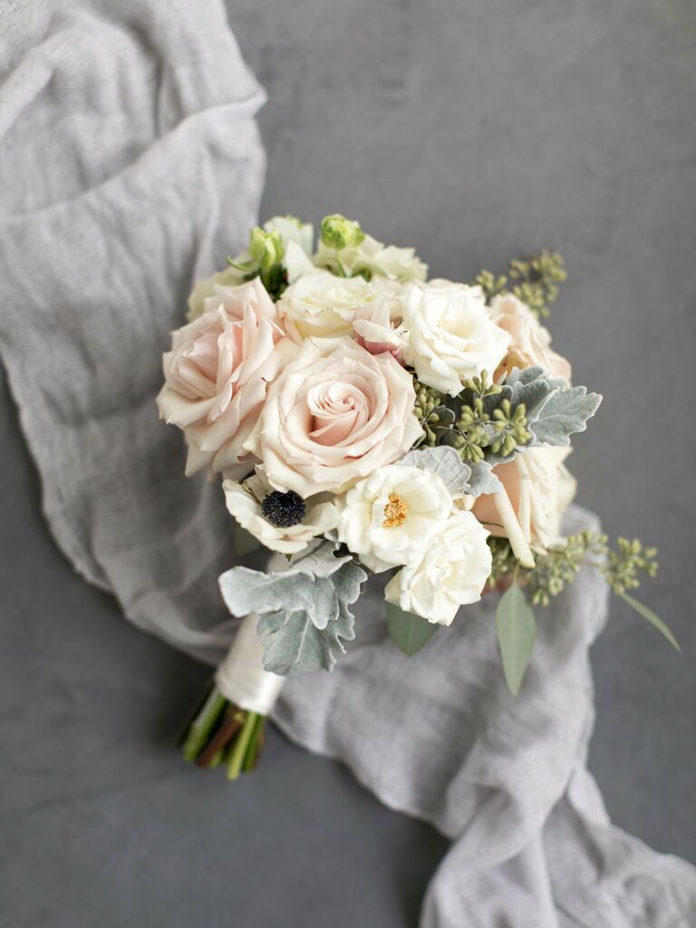 nosegay wedding bouquet with blush roses, lisianthus and dusty miller against a gray fabric backdrop