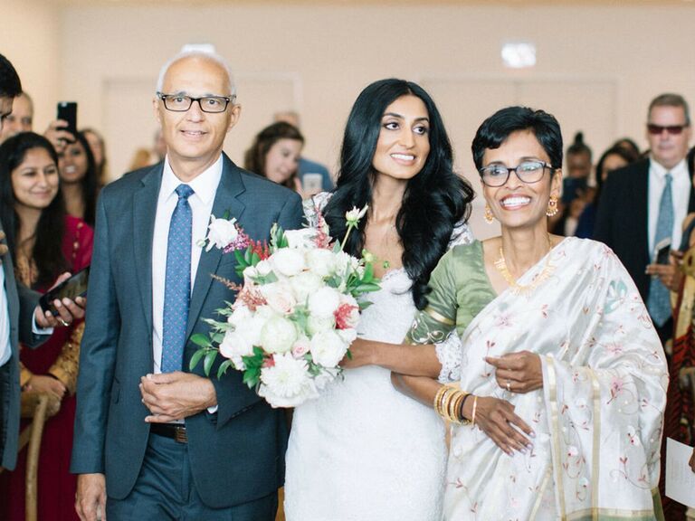 Bride and her parents smile at the crowd. 