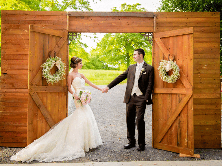 Bride and groom standing in front of a barn doorway.