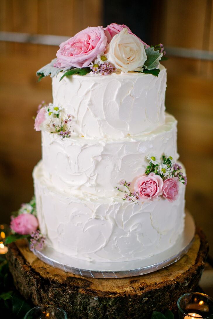 Bethany and Ryan's wedding cake was designed by Sweetri Pastries. Inside, the buttercream cake had two flavors: chocolate cake with mocha fudge ganache and vanilla cake with lemon and raspberry filling. Fresh pink roses and wild flowers topped it off.