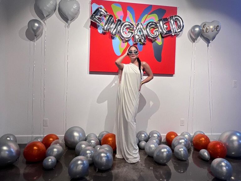 Vanessa poses with balloons that read "engaged."