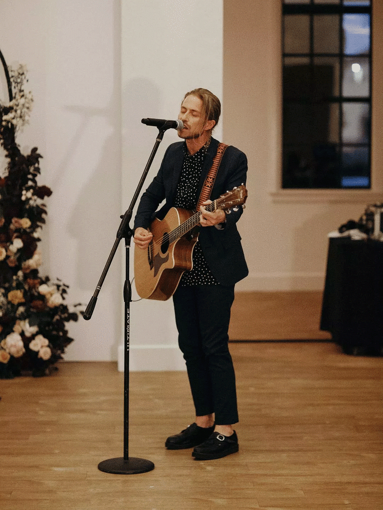Musician playing songs for couples with acoustic guitar.