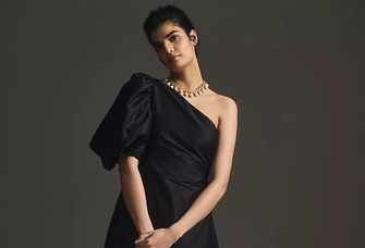 A model poses in a one-shoulder gown with a glamorous puff-sleeve.