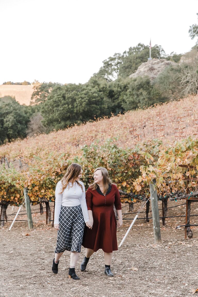 Same-sex engagement photos at vineyard during fall