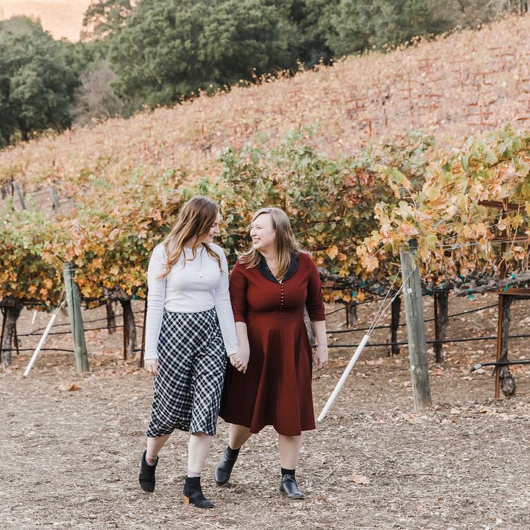Same-sex engagement photos at vineyard during fall