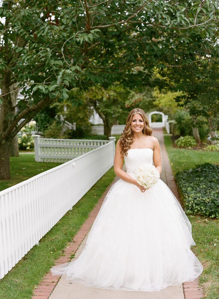 When it came to her wedding day style, Caity kept things classic to suit the wedding’s timeless feel. She had always dreamed of walking down the aisle in a Vera Wang gown, so when it came to finding her dress, she took her mother, mother-in-law, cousin and best friend with her to the designer’s Boston boutique. She settled on a striking ball gown with a strapless, lace bodice and airy organza overlay with delicate lace appliques. She added a crystal belt to give the dress a hint of shimmer and wore a matching Vera Wang veil for the ceremony. “I always wear my hair down and knew I wanted it to wear it down for our wedding,” says Caity. “I wanted to look like myself, but a better version!”