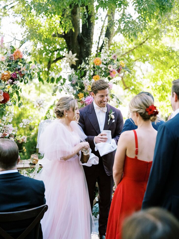 Bride in Pink Tulle Gown, Groom in Dark Maroon Suit Participating in Religious Christian Ceremony, Colorful