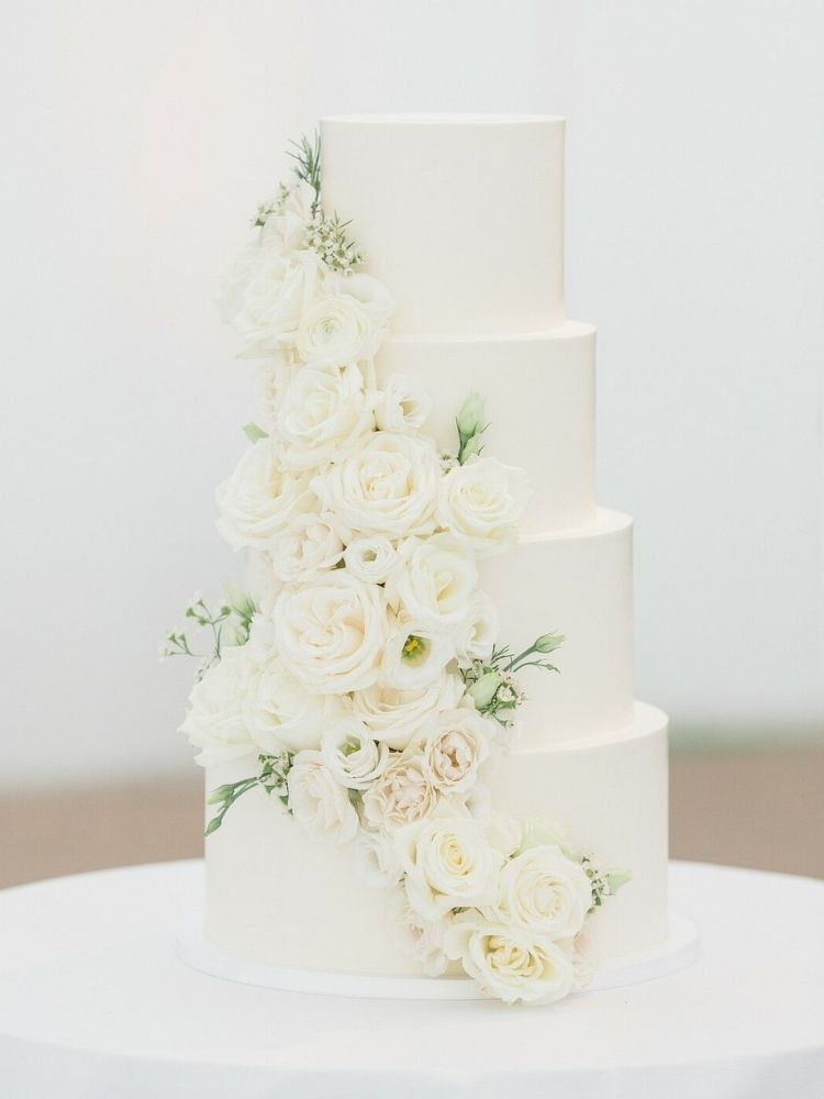 four-tier wedding cake decorated with white roses