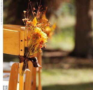 Small orange flower arrangements lined the aisle and were tied with brown satin ribbon to every other chair.
