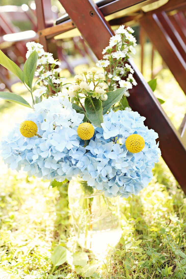 Large Mason jar arrangements of hydrangeas, craspedia and white hypericum berries lined the aisle at the ceremony.