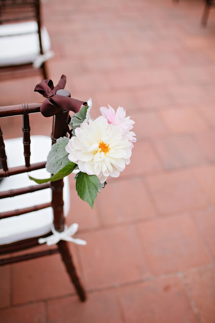 Mason jars tied to ceremony chairs were filled with white and pink dahlias.