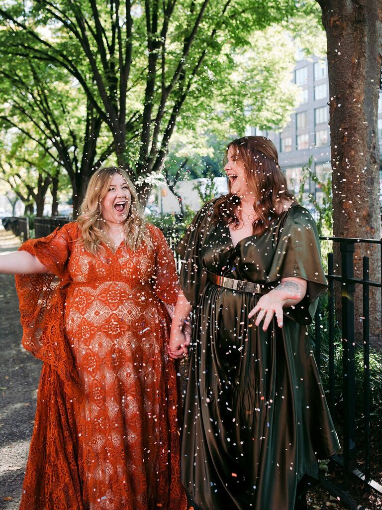 Couple throws confetti in the air while holding hands and smiling. 