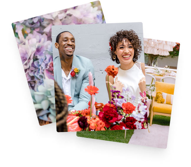 A happy couple sitting behind orange and red flowers.