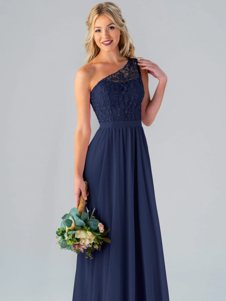 A model shows off a one-shouldered bridesmaid dress with a natural waist and lace bodice.