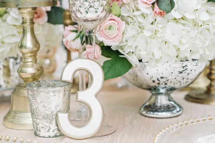 The freestanding table numbers were painted champagne and were propped up against the mercury glass and tall glass candleholders.
