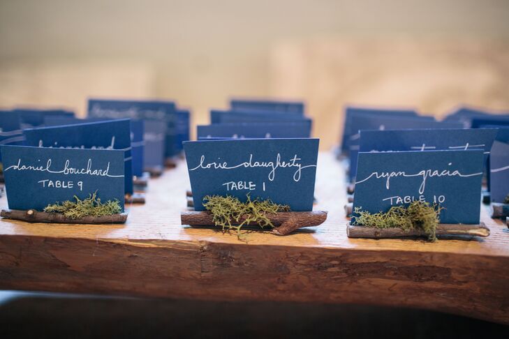 The groom's family helped to create a log escort card holder made from sticks and moss.
