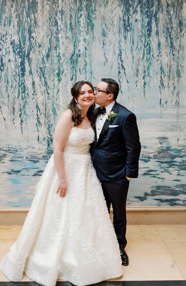Bride in A-Line Dress With Floral Details and Groom in Classic Dark Tuxedo, Cheek Kiss
