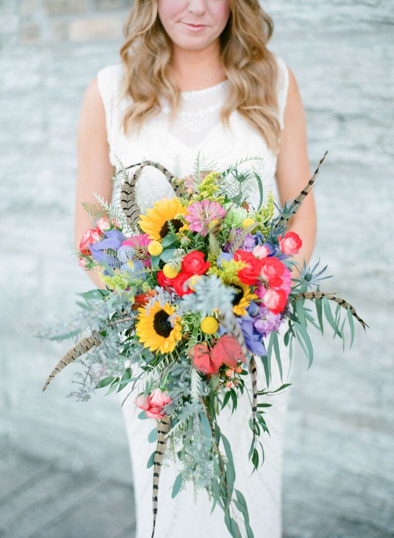 Bride holding bouquet with sunflowers and feathers