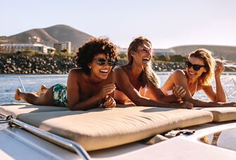 3 women laying out on beach and laughing
